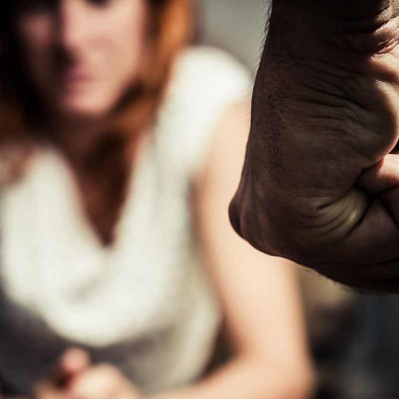 woman sat and with clenched fist in front of her, domestic abuse cases during COVID